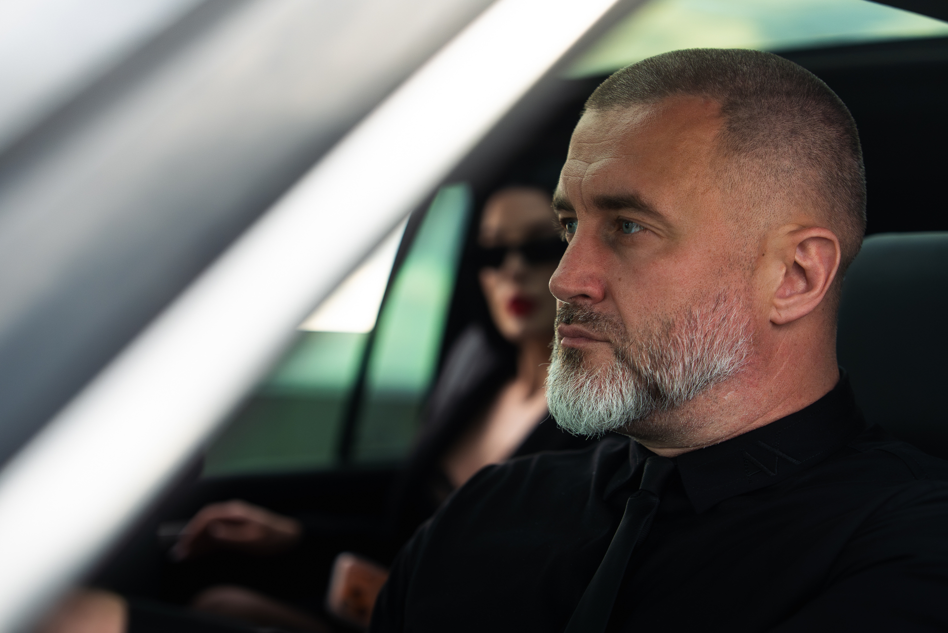 Professional chauffeur in black with VIP client in back seat